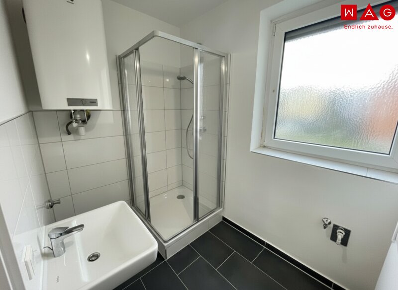 Badezimmer nach Sanierung mit Dusche und Fenster Symbolfoto