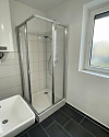 Badezimmer nach Sanierung mit Dusche und Fenster Symbolfoto
